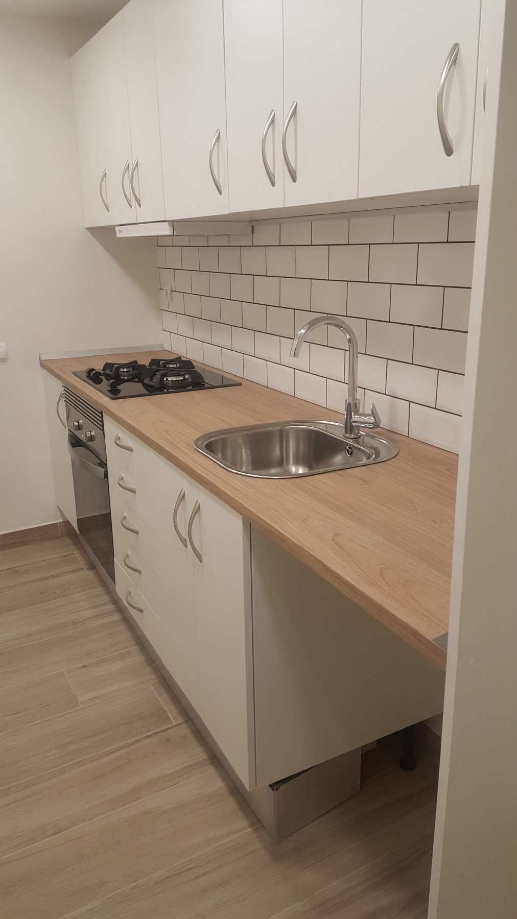 Cocina blanca con encimera de madera y azulejo metro en Barcelona