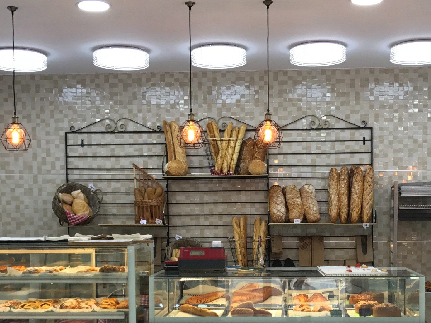Interior de panadería reformada con estanterías de hierro y vitrinas de pan artesano en Barcelona