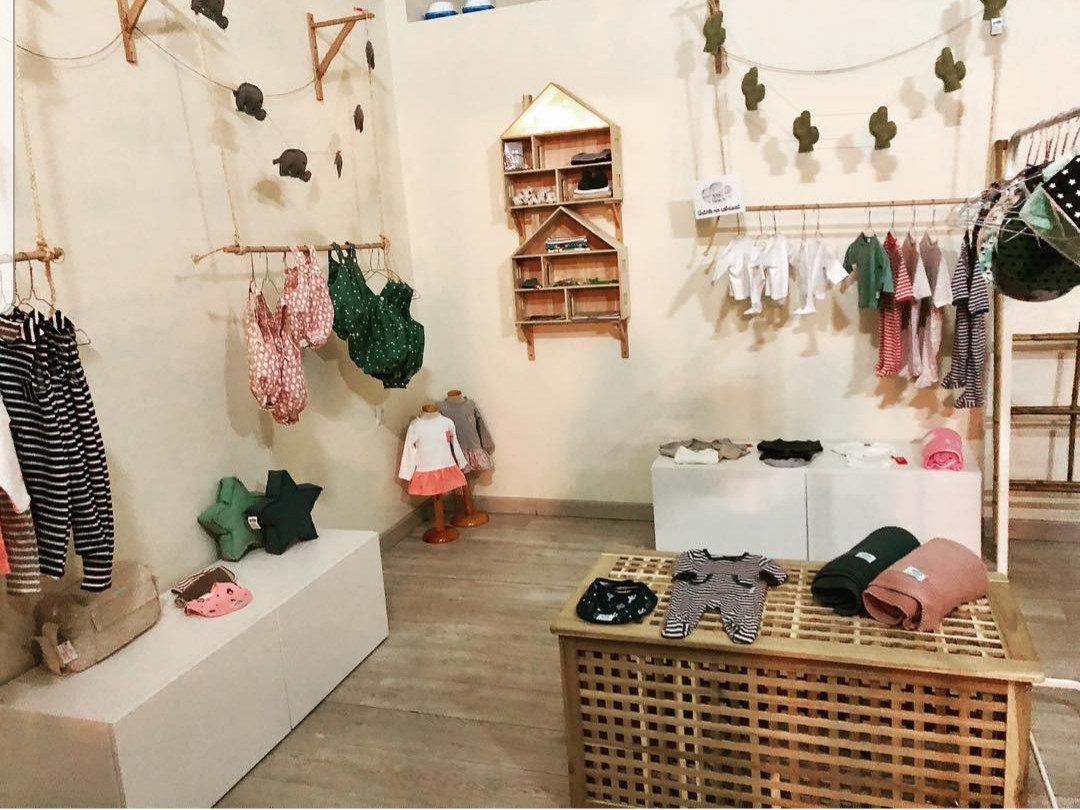Interior de la tienda infantil El Petit Núvol con estanterías y percheros de madera en Esplugues de Llobregat