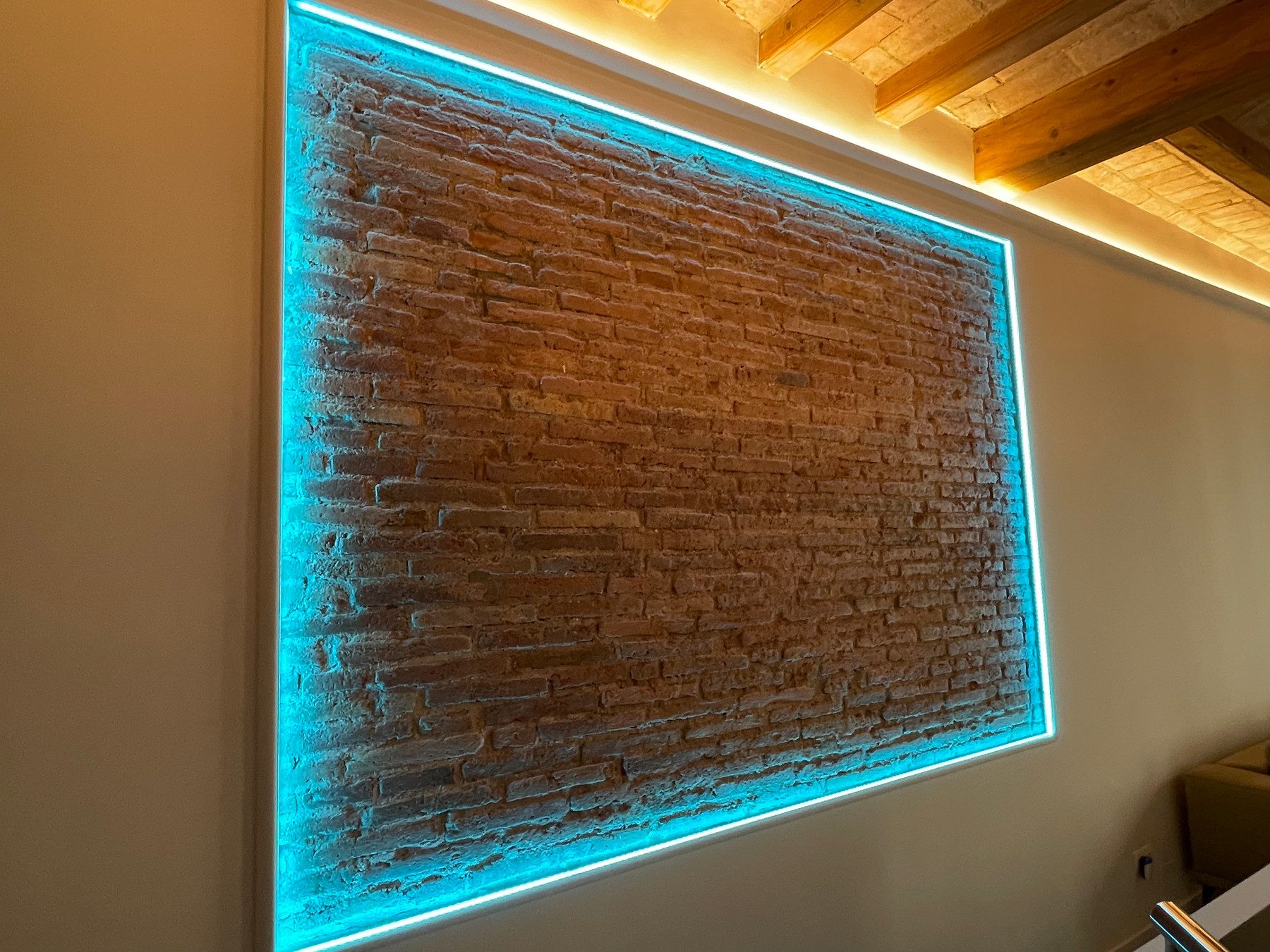 Detalle de pared de ladrillo visto con marco de luz LED en una reforma integral en Carrer Viladomat, Barcelona