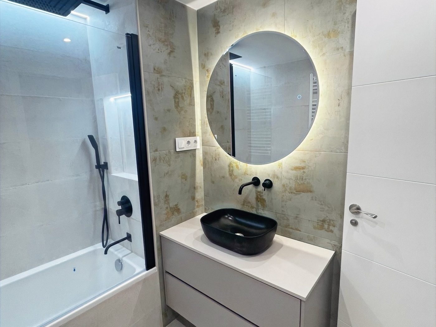 Baño reformado con espejo redondo iluminado en Castelldefels