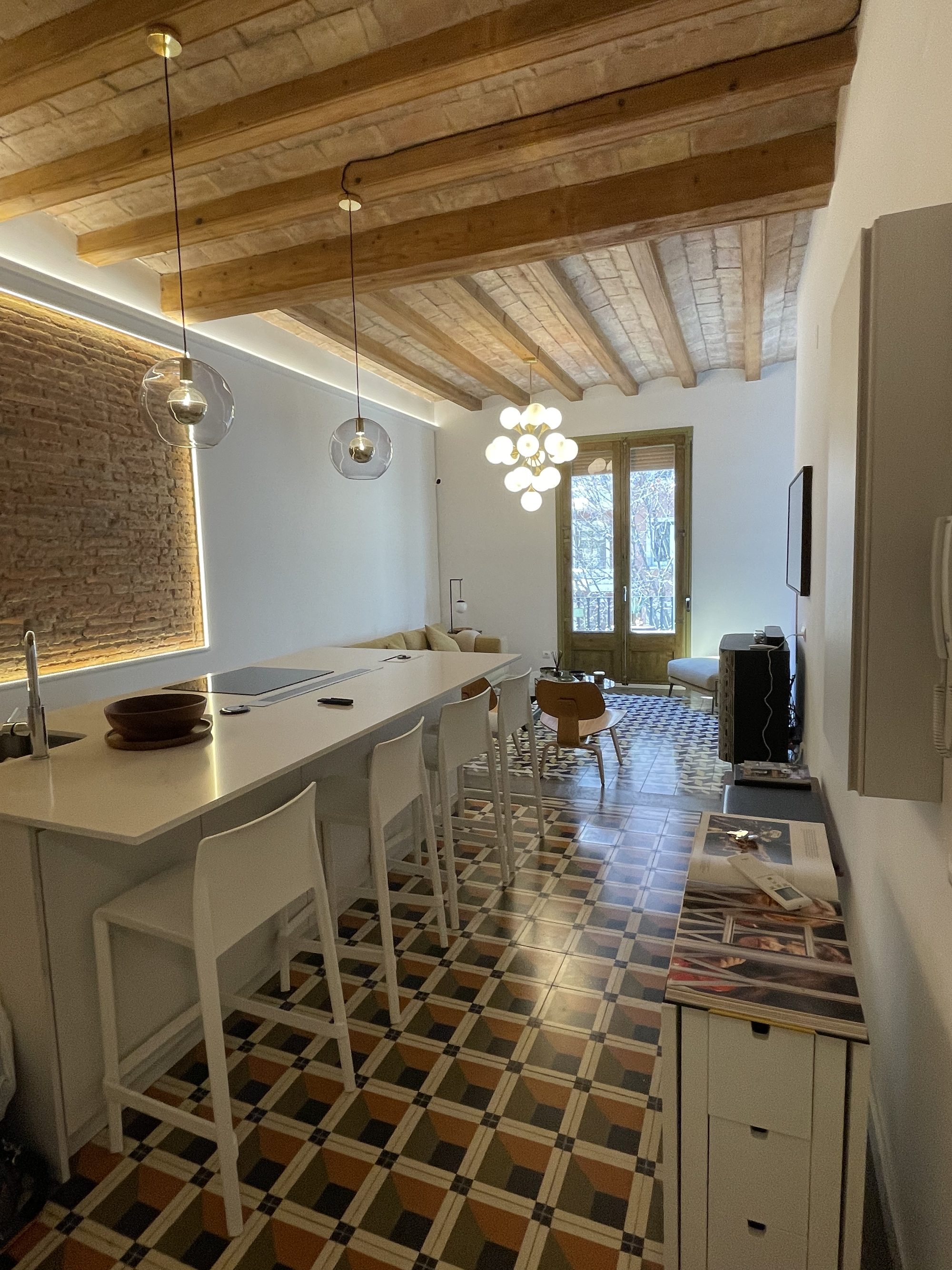 Salón reformado con techo de obra vista, vigas de madera y suelo hidráulico original